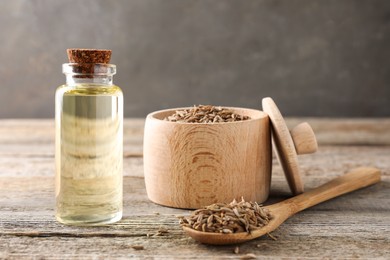 Caraway (Persian cumin) seeds and essential oil on wooden table