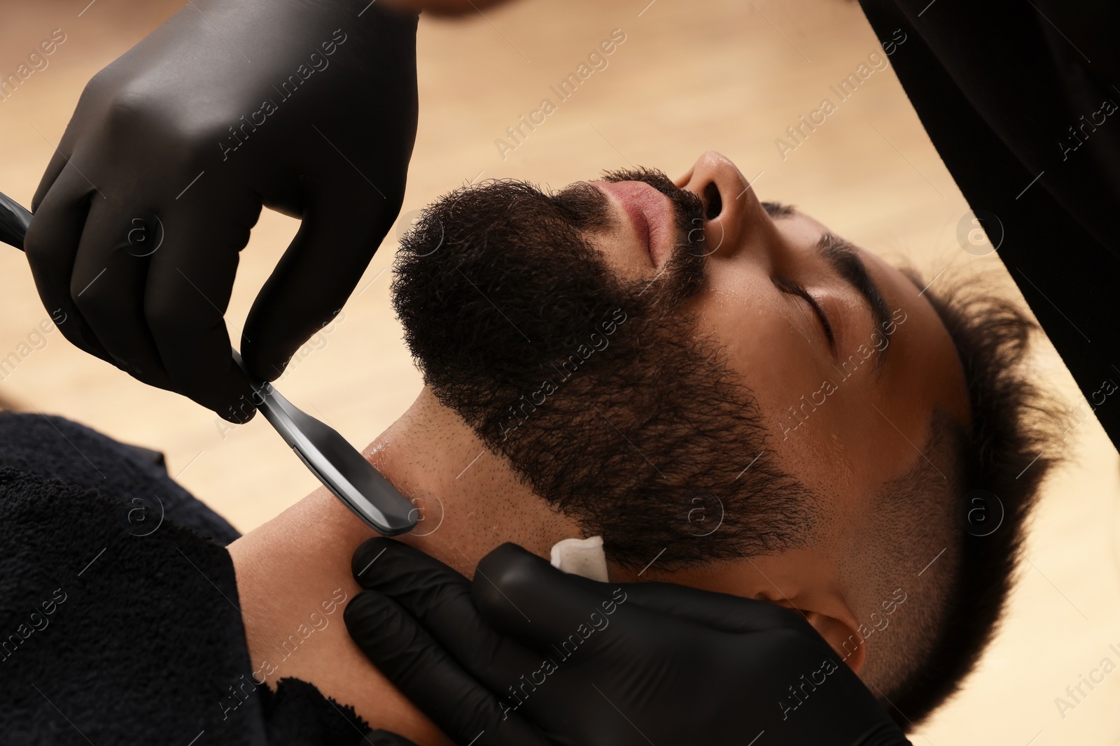 Photo of Professional hairdresser working with client in barbershop, closeup