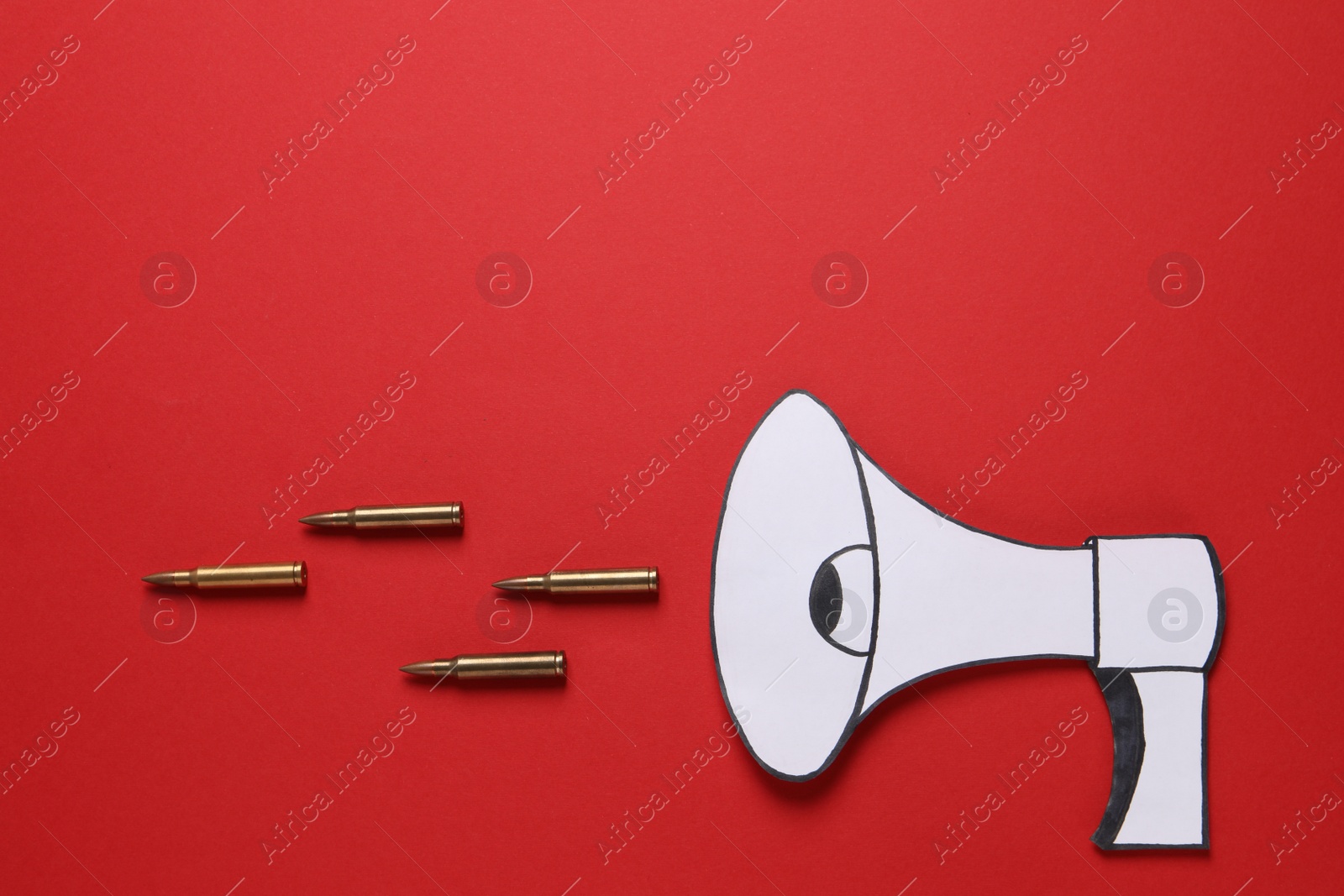 Photo of Paper loudspeaker and bullets on red background, flat lay with space for text. Hybrid warfare concept