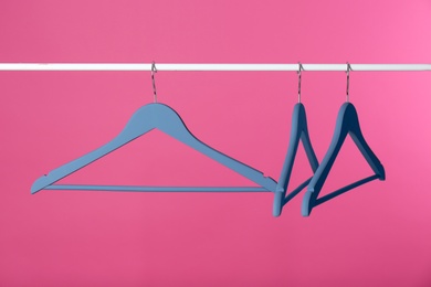 Metal rack with clothes hangers on color background