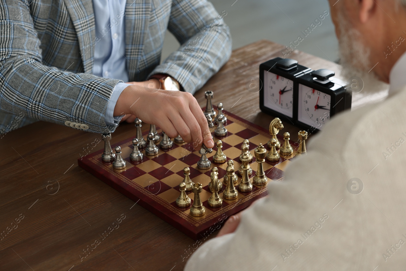 Photo of Men playing chess during tournament at wooden table, closeup