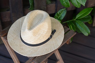 Photo of Stylish hat on wooden stool near fence. Beach accessory