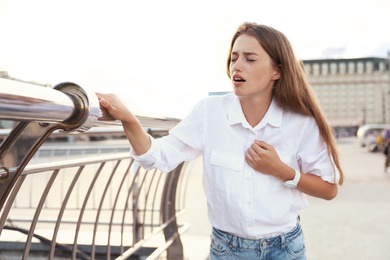 Young woman having heart attack on city street