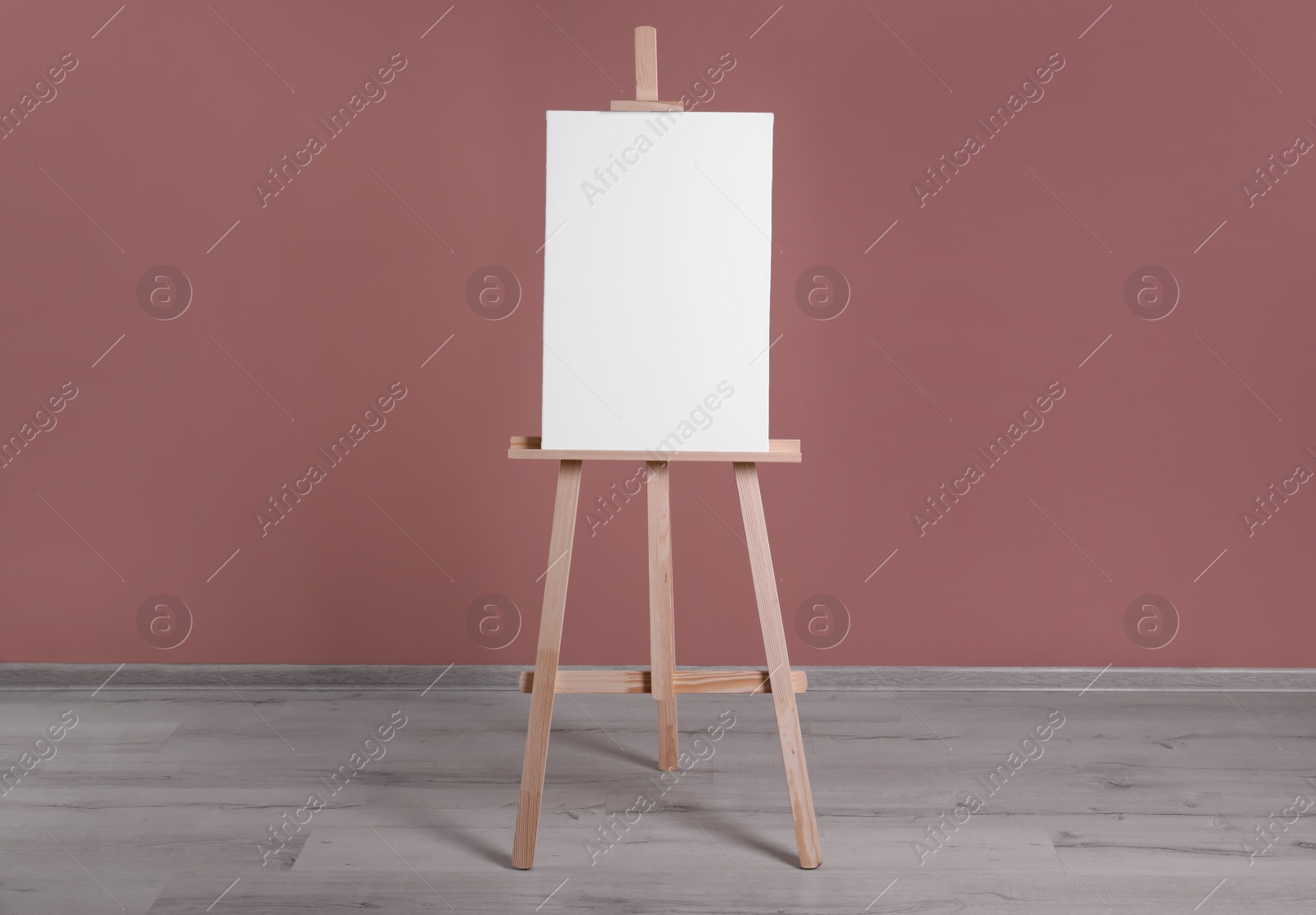 Photo of Wooden easel with blank canvas near dusty rose wall