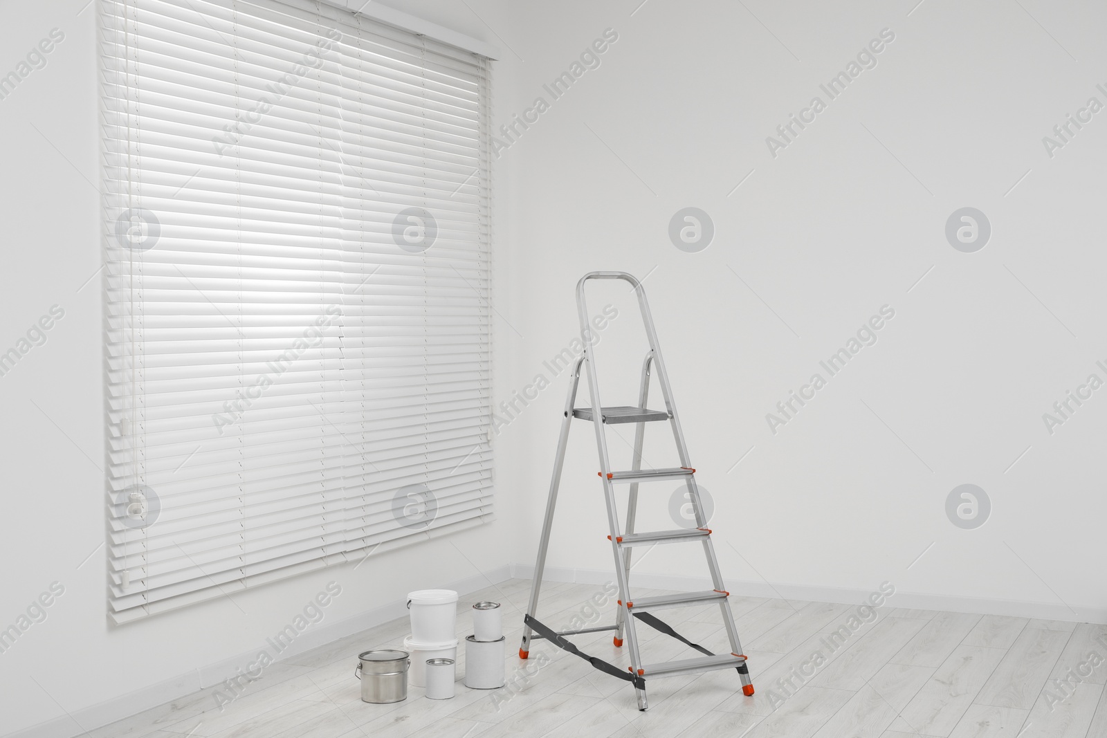 Photo of Metallic folding ladder and painting tools indoors