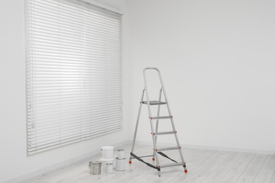 Metallic folding ladder and painting tools indoors