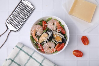 Bowl of delicious salad with seafood on white tiled table, flat lay