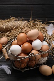 Photo of Fresh chicken eggs and dried straw on black wooden table