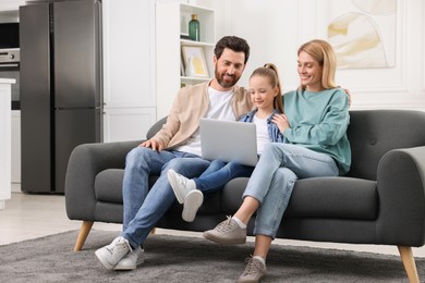 Photo of Happy family spending time together and using laptop on sofa at home