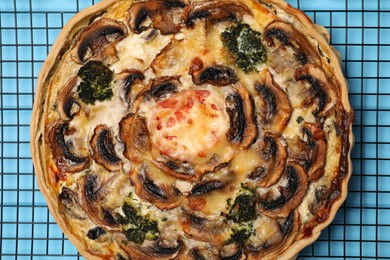 Photo of Delicious quiche with mushrooms on light blue table, closeup
