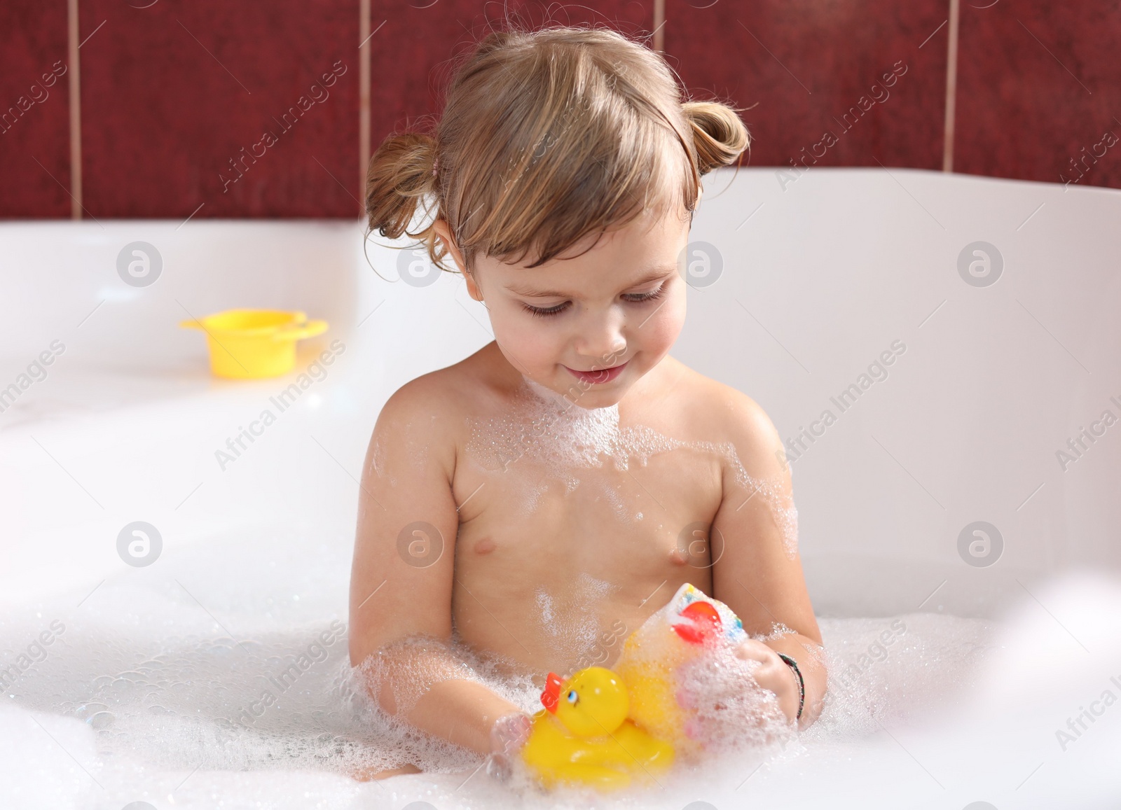 Photo of Little girl bathing with toy ducks in tub