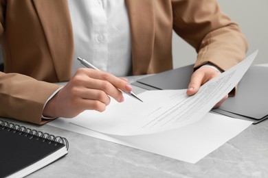 Photo of Woman signing document at light grey marble table, closeup