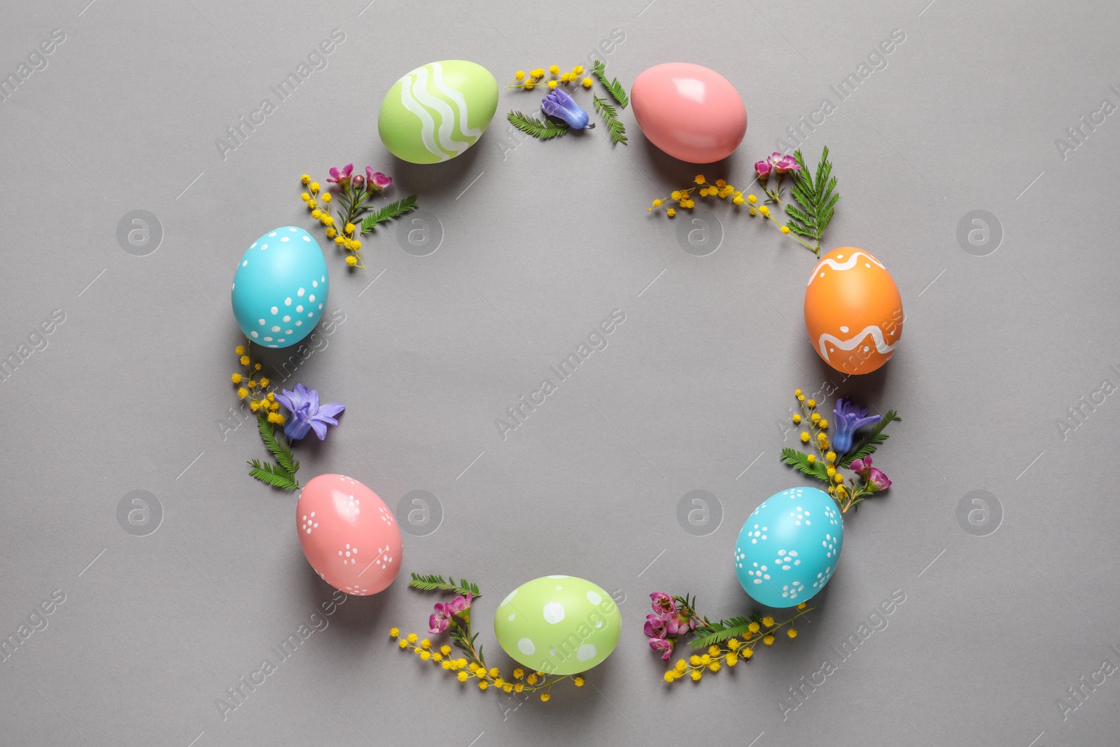 Photo of Flat lay composition of painted Easter eggs and flowers on color background, space for text