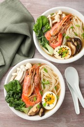 Delicious ramen with shrimps in bowls served on wooden table, flat lay. Noodle soup