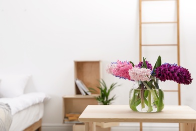 Photo of Beautiful hyacinths in glass vase on table indoors, space for text. Spring flowers