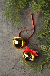 Photo of Golden sleigh bells and fir branches on grey background, flat lay