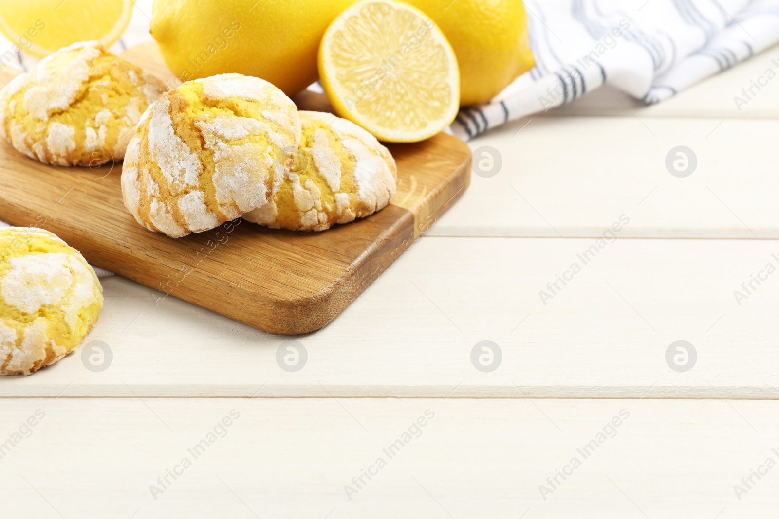 Photo of Tasty homemade lemon cookies and fresh fruits on white wooden table. Space for text