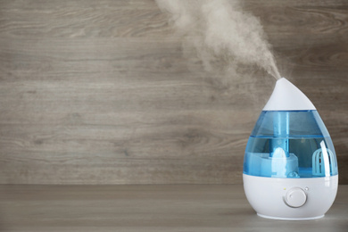 Modern air humidifier on wooden table. Space for text