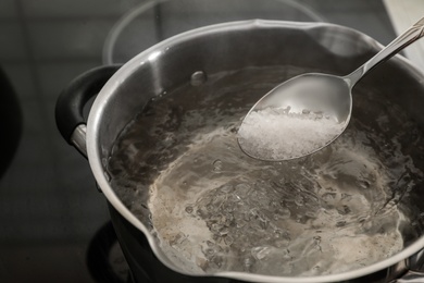 Photo of Salting boiling water in pot on stove, closeup