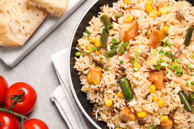 Delicious rice pilaf with chicken and vegetables on light grey table, closeup