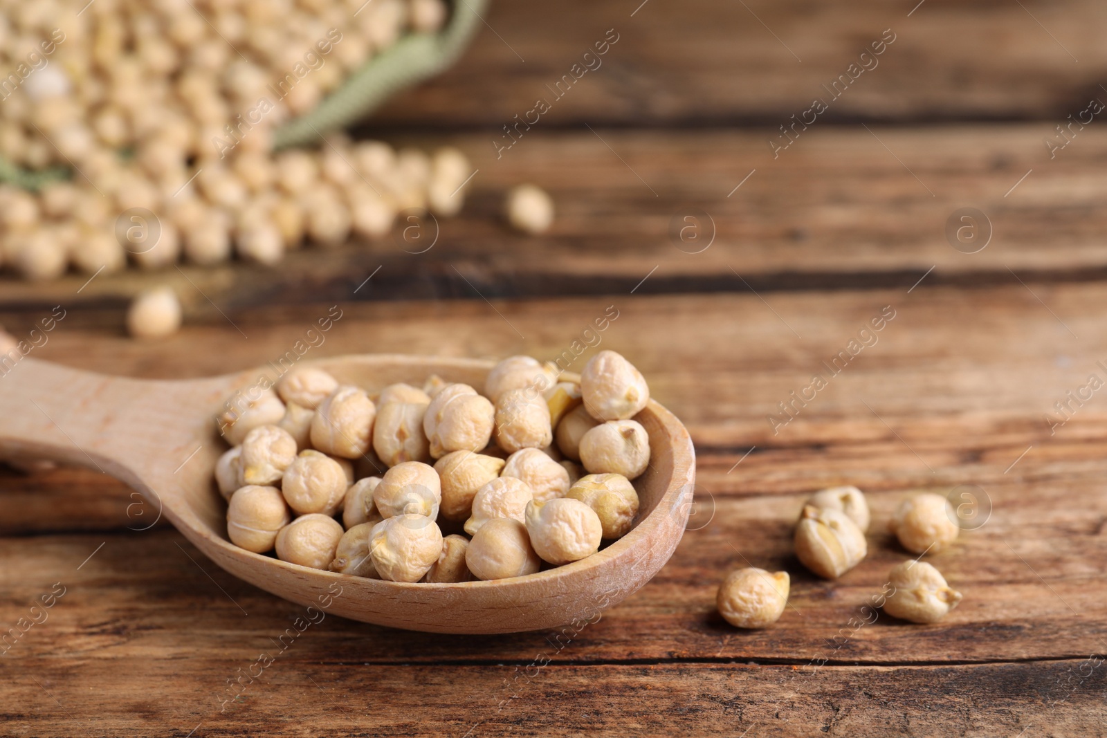 Photo of Spoon with chickpeas on wooden table, closeup. Space for text