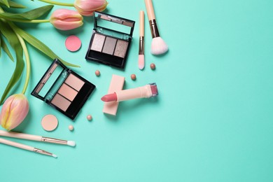 Photo of Flat lay composition with different makeup products and beautiful tulips on light turquoise background. Space for text