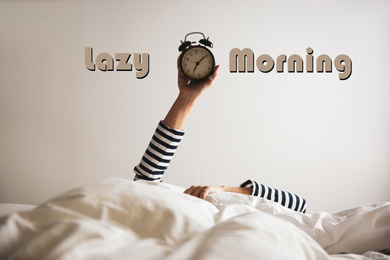 Image of Woman with alarm clock lying in bed, closeup. Lazy morning