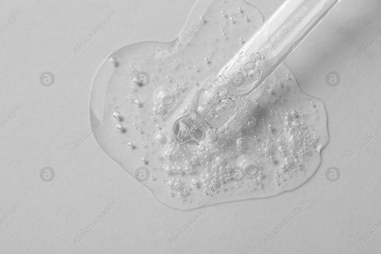 Photo of Pipette with cosmetic serum on white background, macro view