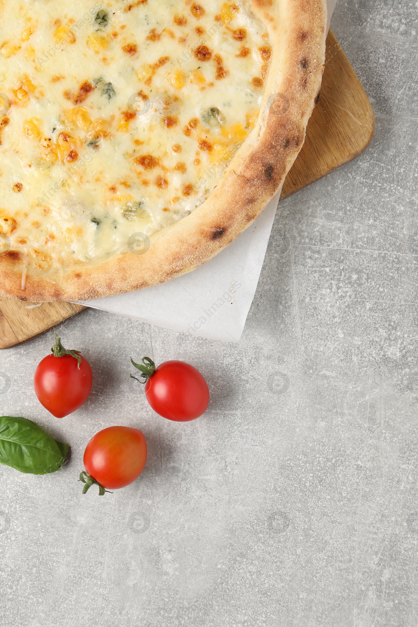 Photo of Delicious cheese pizza, basil and tomatoes on light grey table, flat lay. Space for text