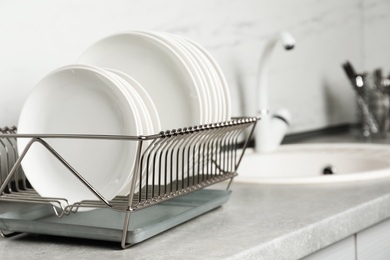 Drying rack with clean dishes on kitchen counter. Space for text