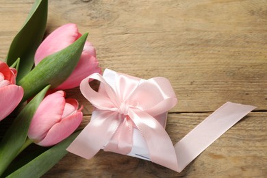 Happy Mother's Day. Beautiful pink tulips and gift box on wooden table, flat lay. Space for text