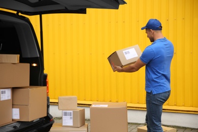Courier with parcels near delivery van outdoors