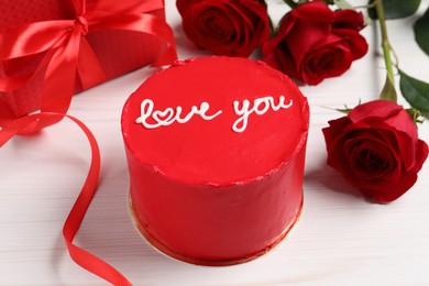 Bento cake with text Love You, gift box and roses on white wooden table. St. Valentine's day surprise