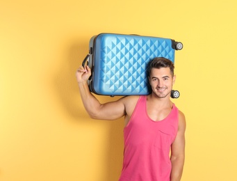 Photo of Young man with suitcase on color background