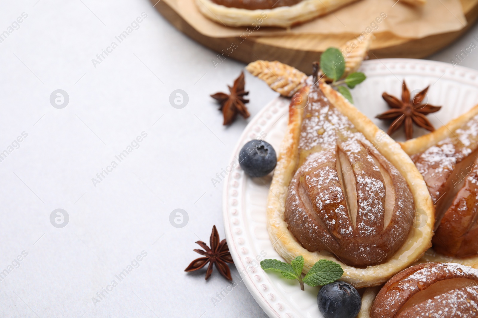 Photo of Delicious pears baked in puff pastry with powdered sugar served on light grey table, closeup. Space for text