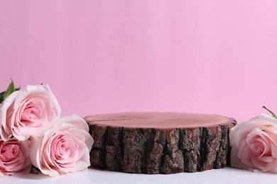 Photo of Presentation for product. Wooden podium and beautiful roses against light pink background, space for text