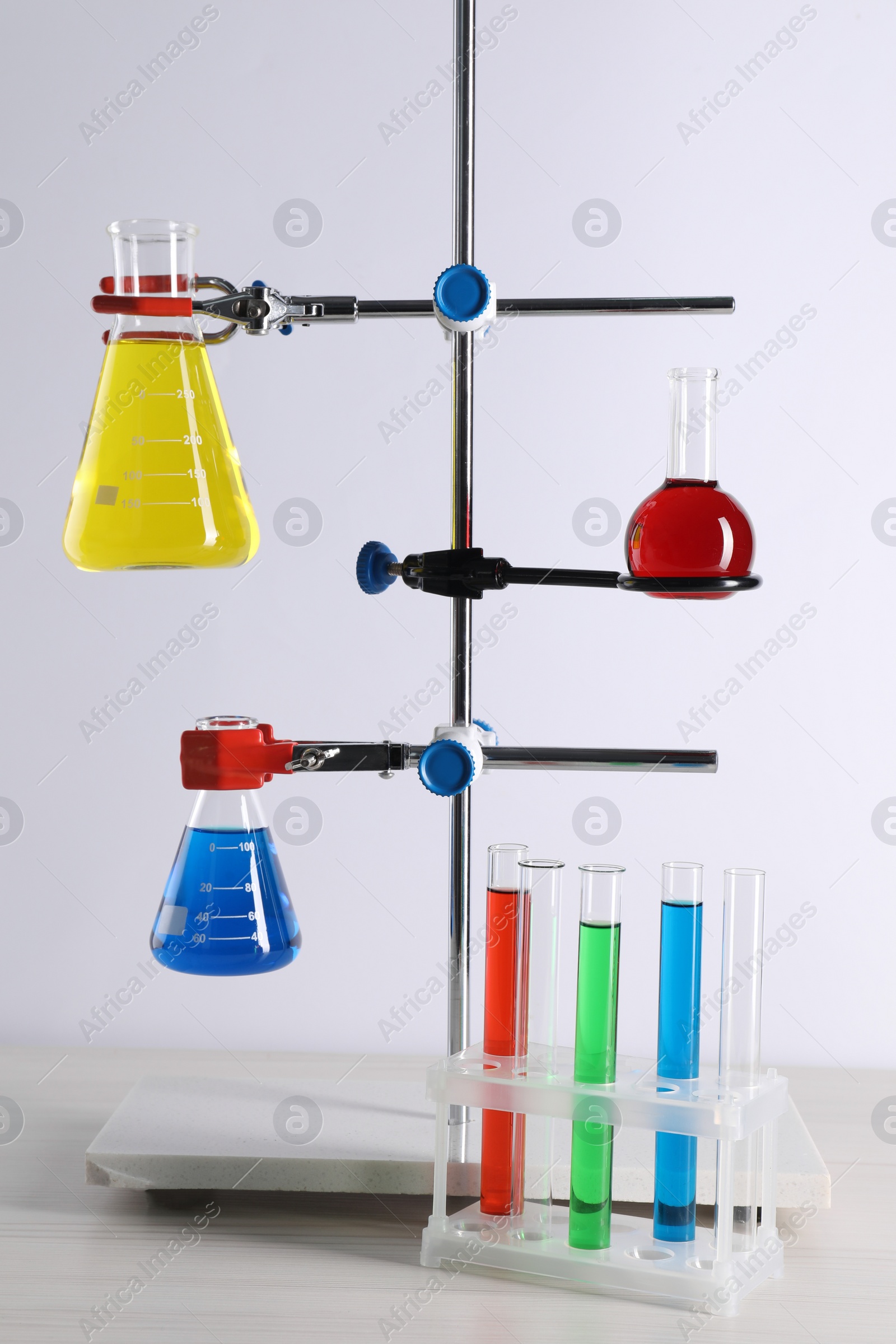 Photo of Laboratory glassware with liquids on table against white background