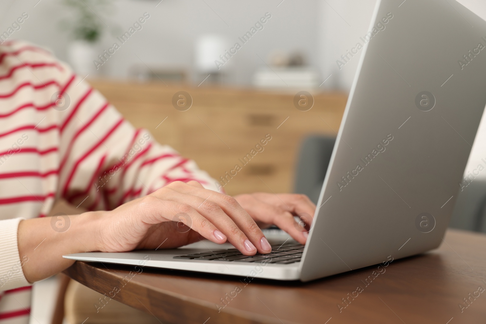 Photo of Woman using laptop at wooden coffee table in room, closeup