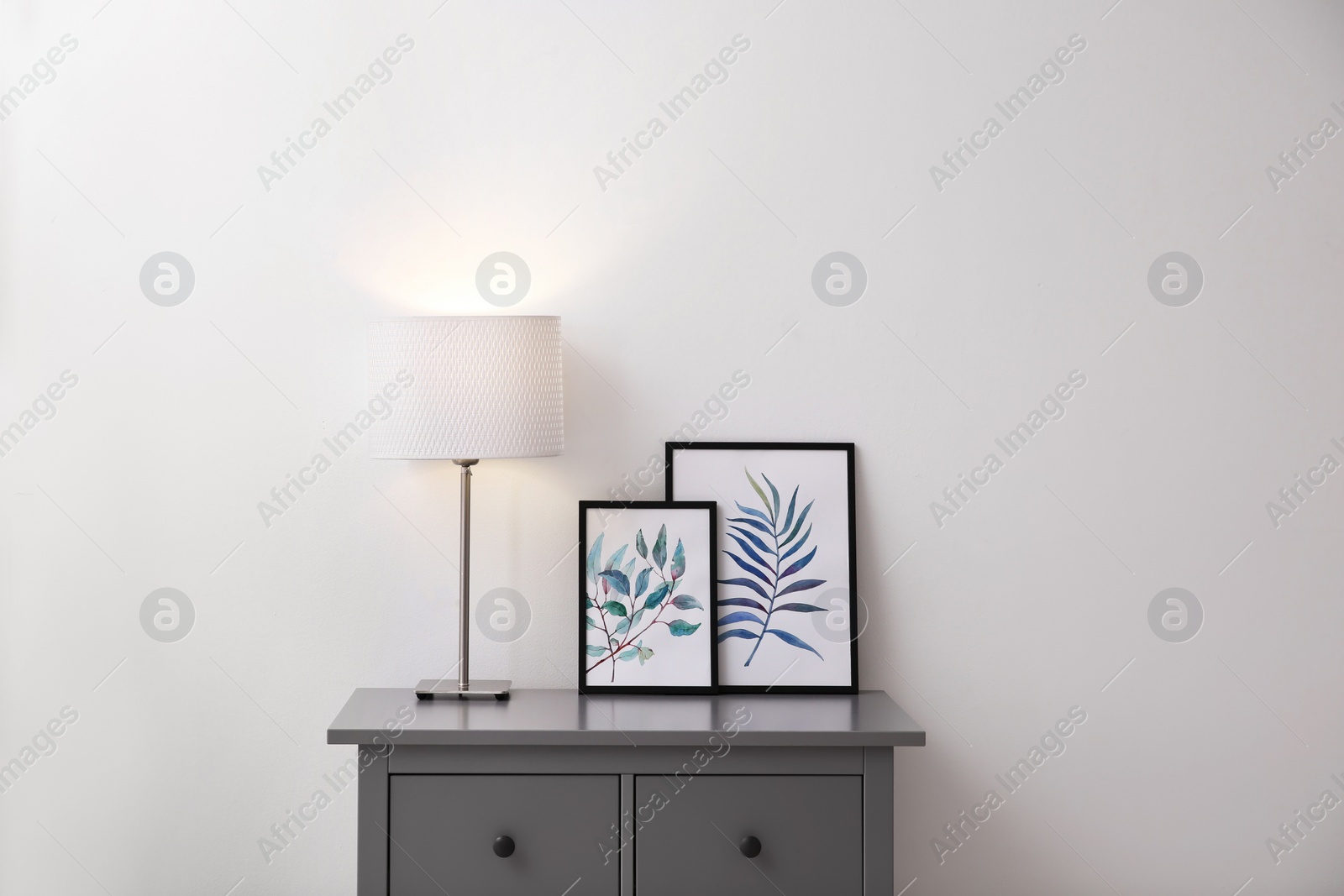 Photo of Modern grey chest of drawers near light wall in room. Interior design