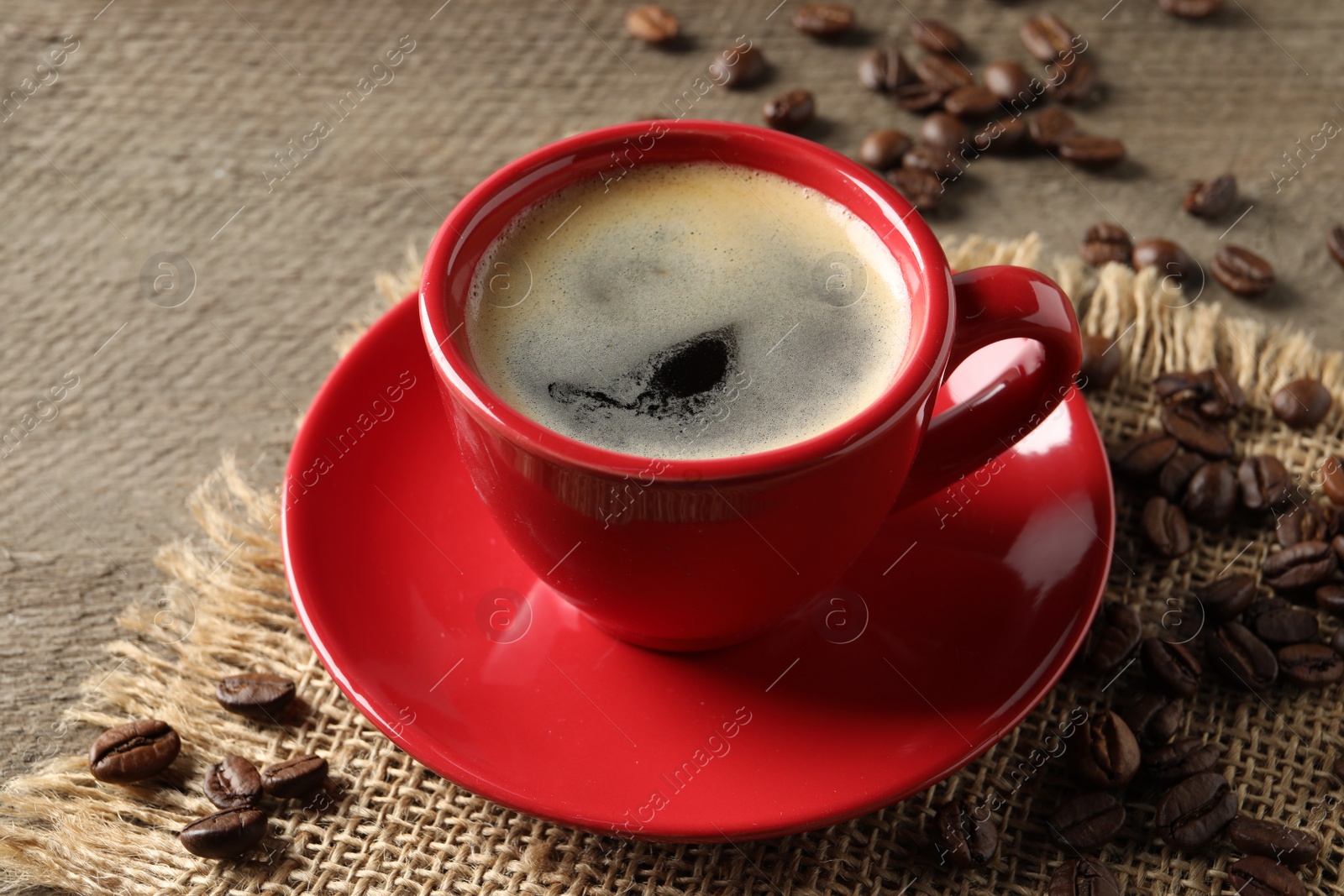 Photo of Cup of aromatic coffee and beans on wooden table