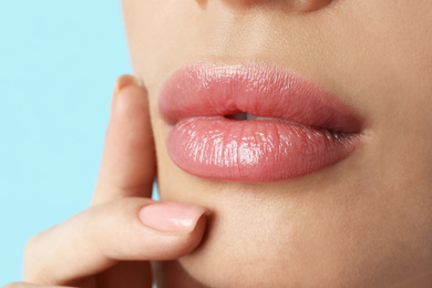 Photo of Woman with beautiful full lips on light blue background, closeup