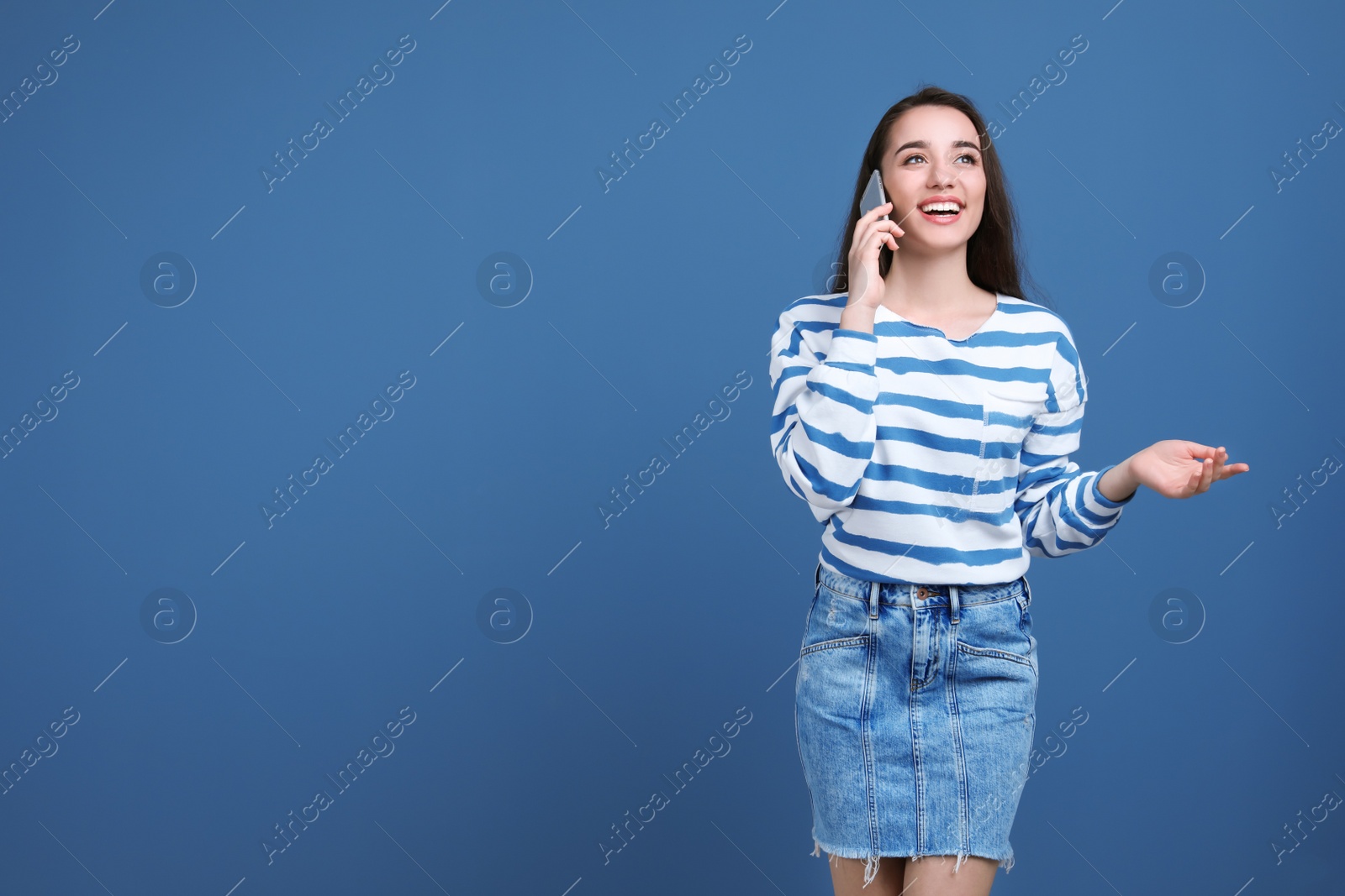 Photo of Young woman talking on phone against color background