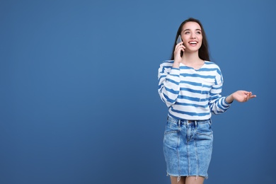 Young woman talking on phone against color background