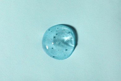 Photo of Sample of transparent cosmetic gel on light blue background, top view