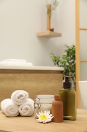 Photo of Different spa products and beautiful flower on wooden table in bathroom