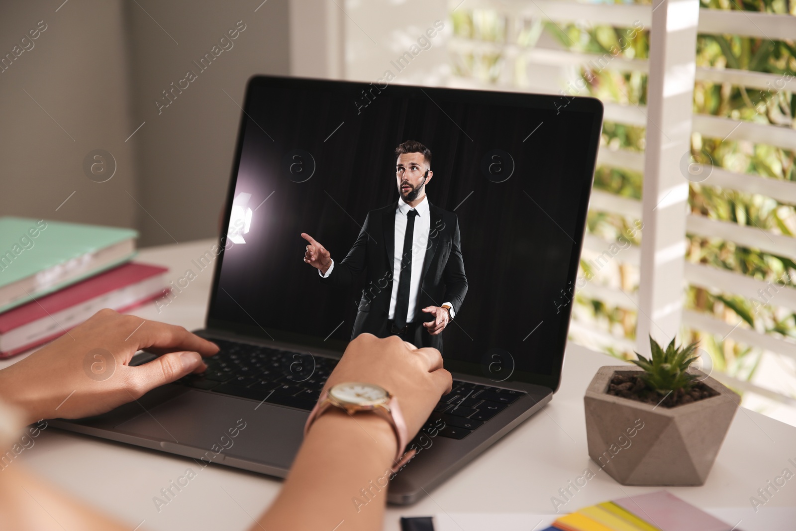 Image of Woman watching performance of motivational speaker on laptop at white table, closeup