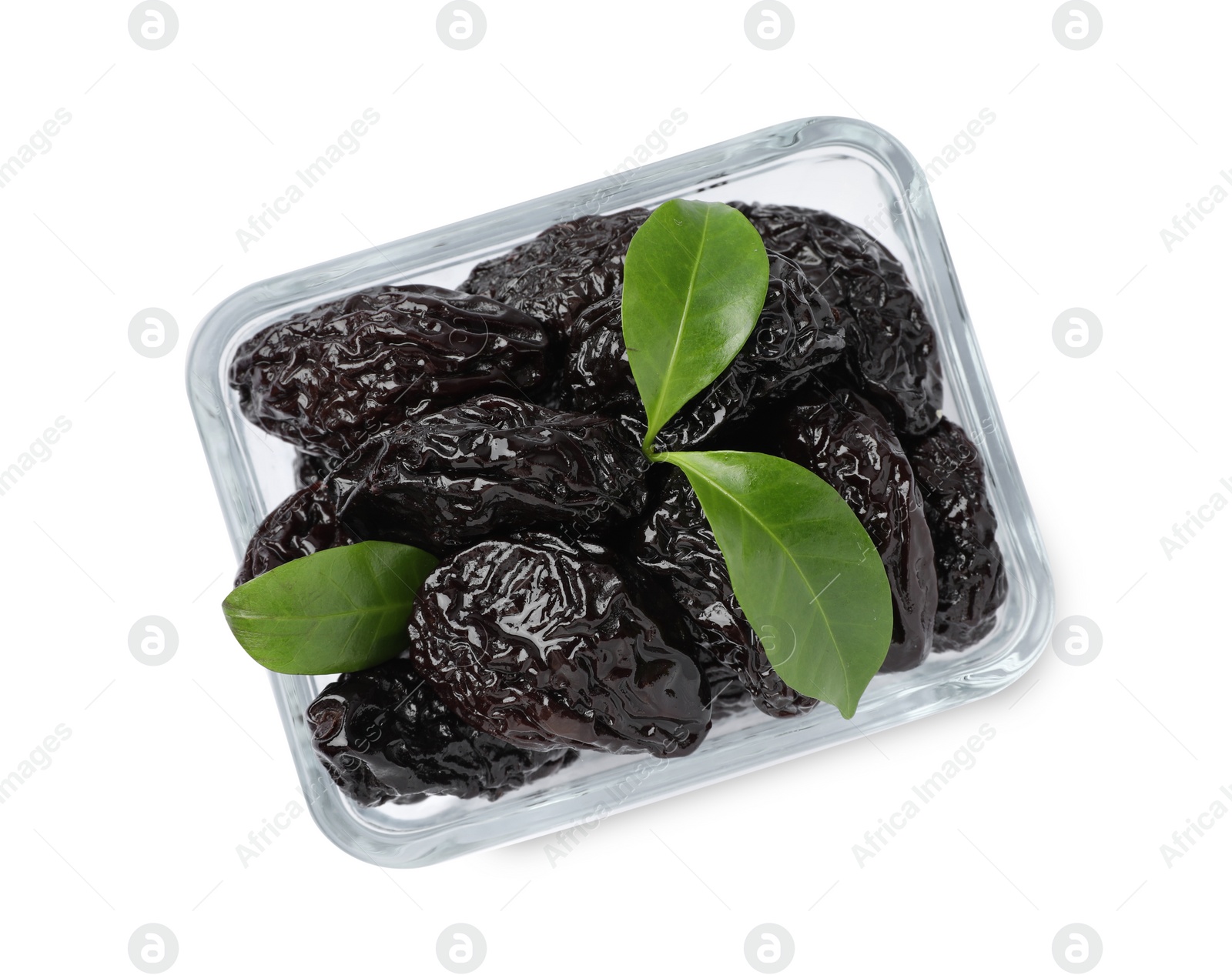 Photo of Bowl with sweet dried prunes and green leaves isolated on white, top view