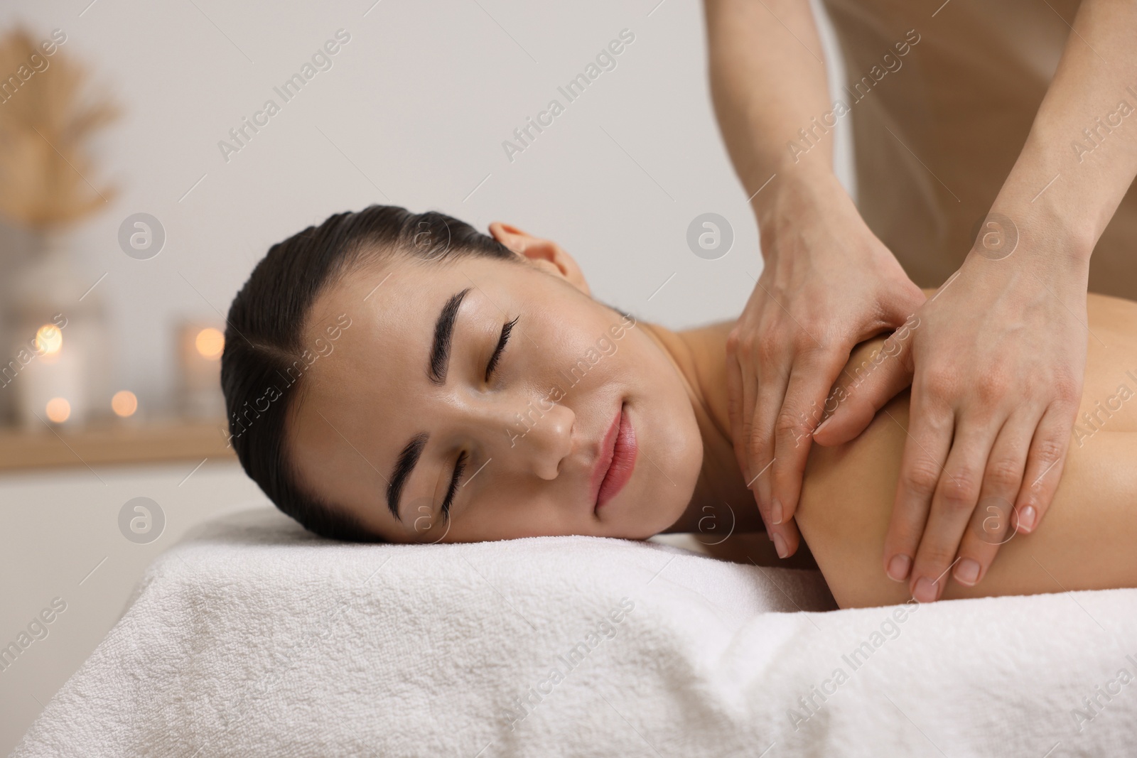 Photo of Woman receiving back massage on couch in spa salon