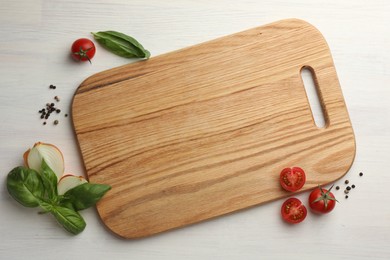 Photo of Cutting board, basil, onion, pepper and tomatoes on white wooden table, flat lay. Space for text