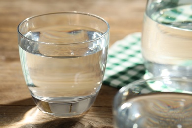 Photo of Glasses of water on wooden table, closeup. Refreshing drink